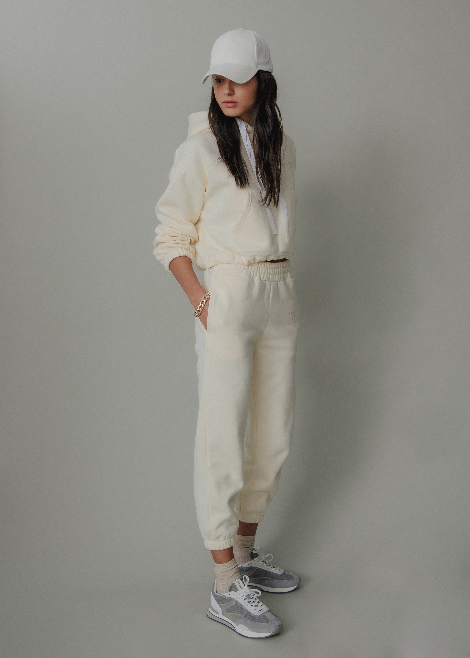 Person wearing a white outfit with a cap against a gray background
