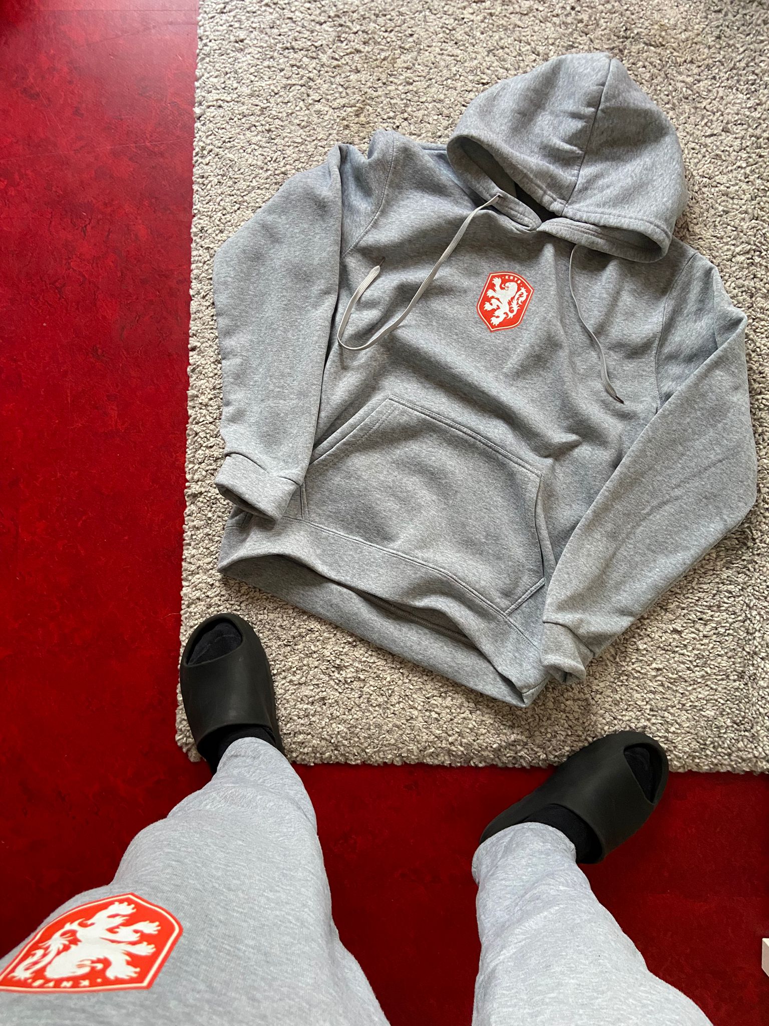 Gray hoodie with a red logo on a red floor