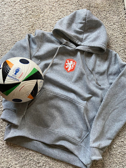 Gray hoodie with a logo next to a soccer ball on a carpeted floor