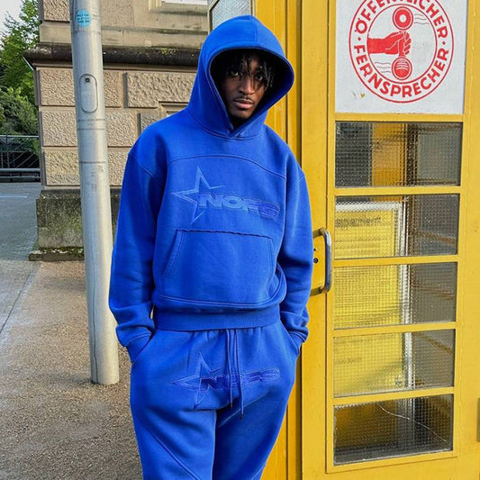 Person wearing a blue tracksuit standing in front of a yellow door with a sign.