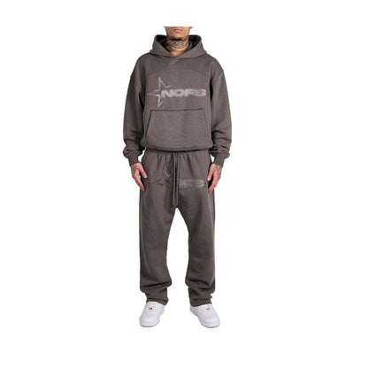 Person wearing a gray hoodie and pants set with a logo on a white background