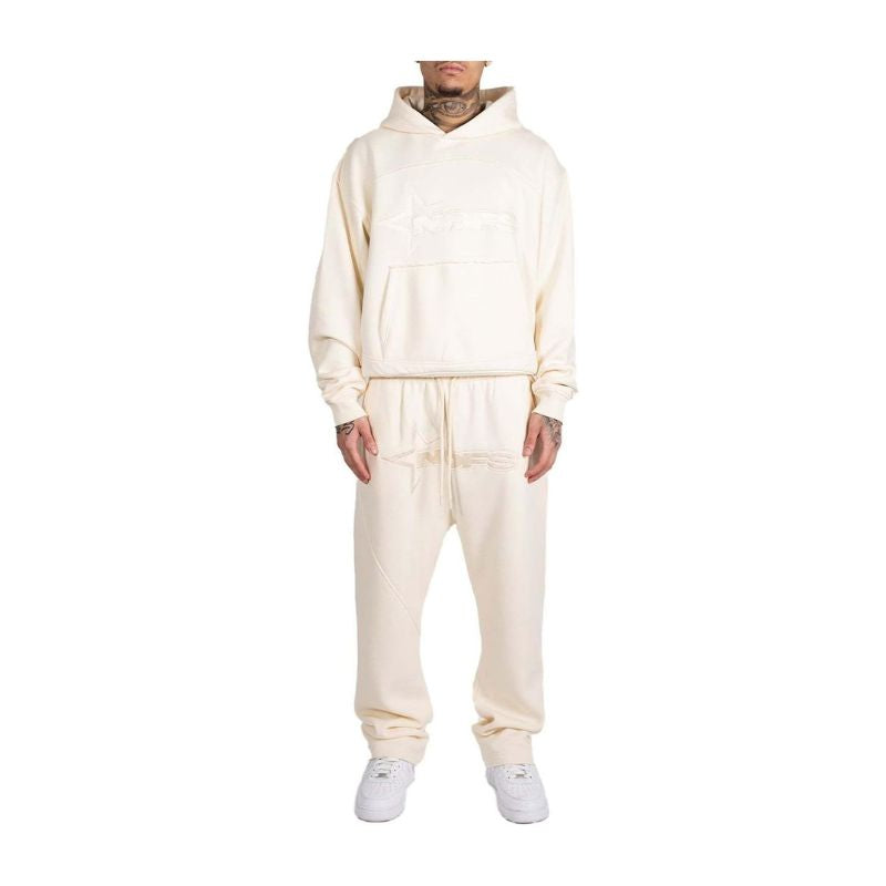 Person wearing a cream-colored tracksuit on a white background
