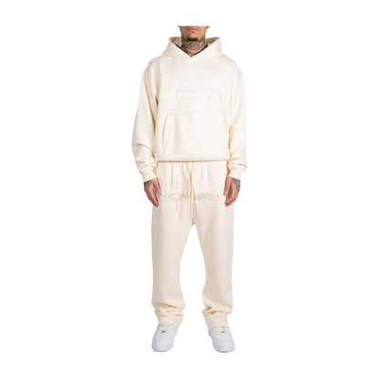 Person wearing a cream-colored tracksuit on a white background