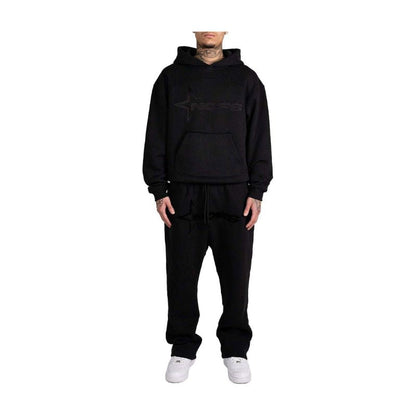 Person wearing a black hoodie and pants set with a brand logo on a white background