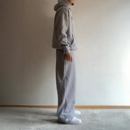 Person wearing a gray tracksuit standing against a plain wall.