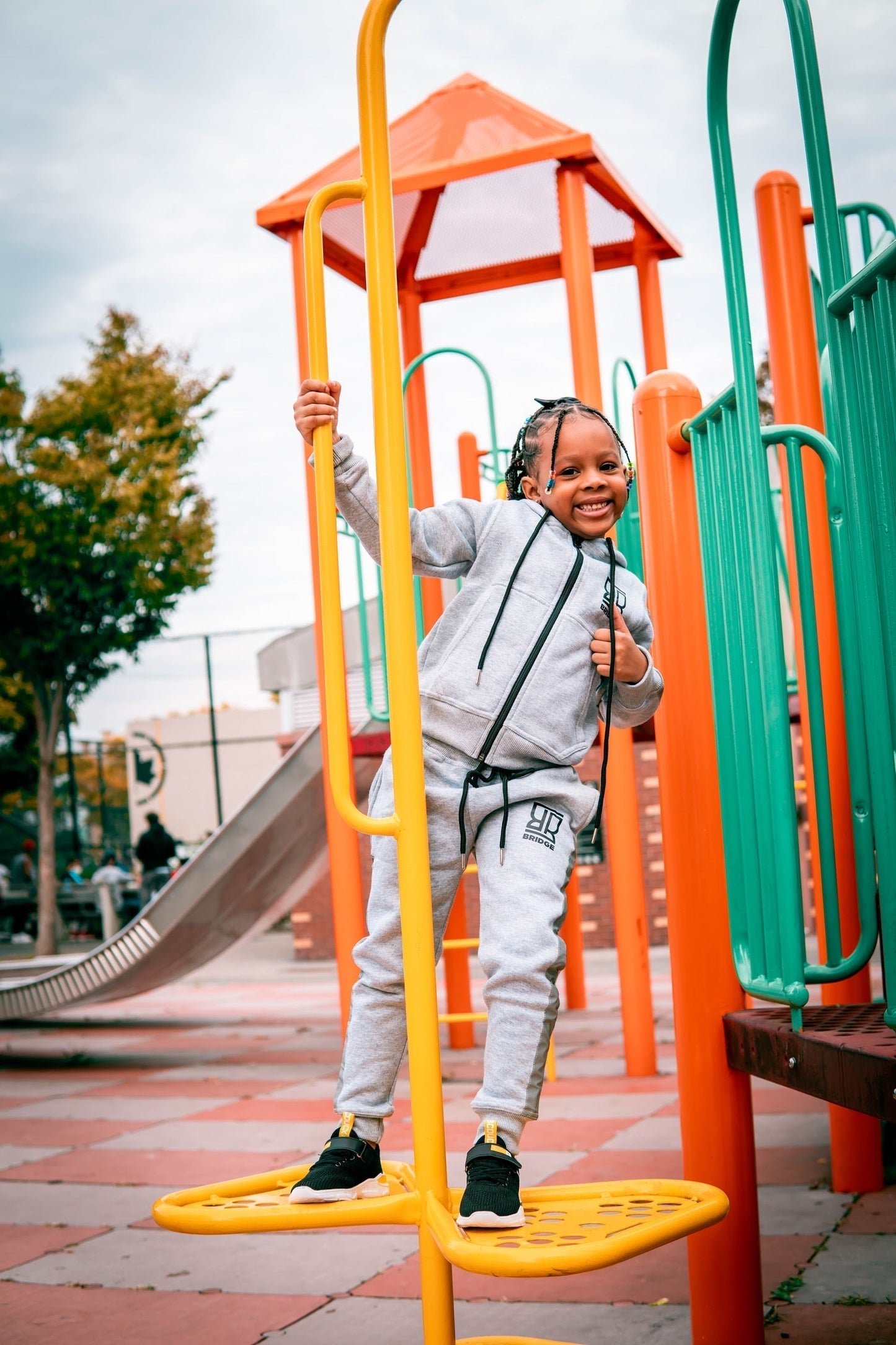 Child playing on a colorful playground structure with trees and buildings in the background.