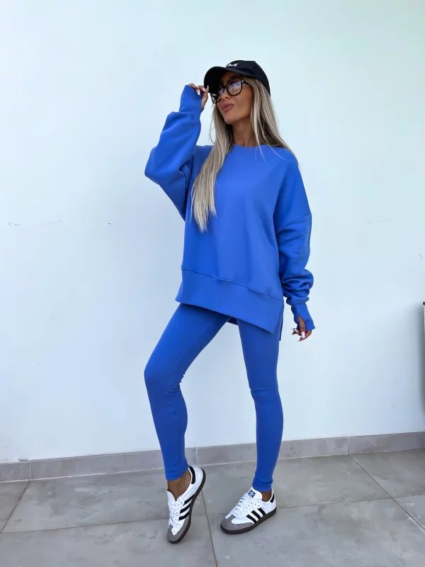 Person wearing a blue outfit with a white wall background