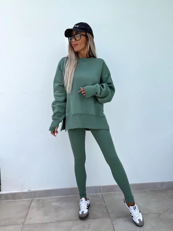 Person wearing a green tracksuit with a white wall background