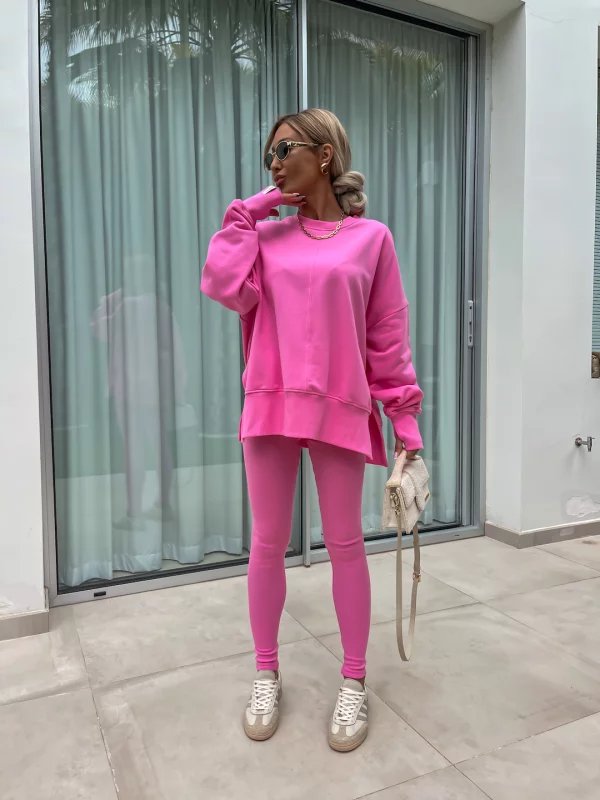Person wearing a bright pink outfit standing in front of a glass door.