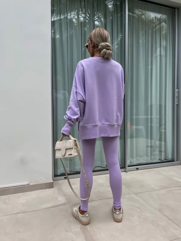 Person wearing a purple outfit standing in front of a glass door.