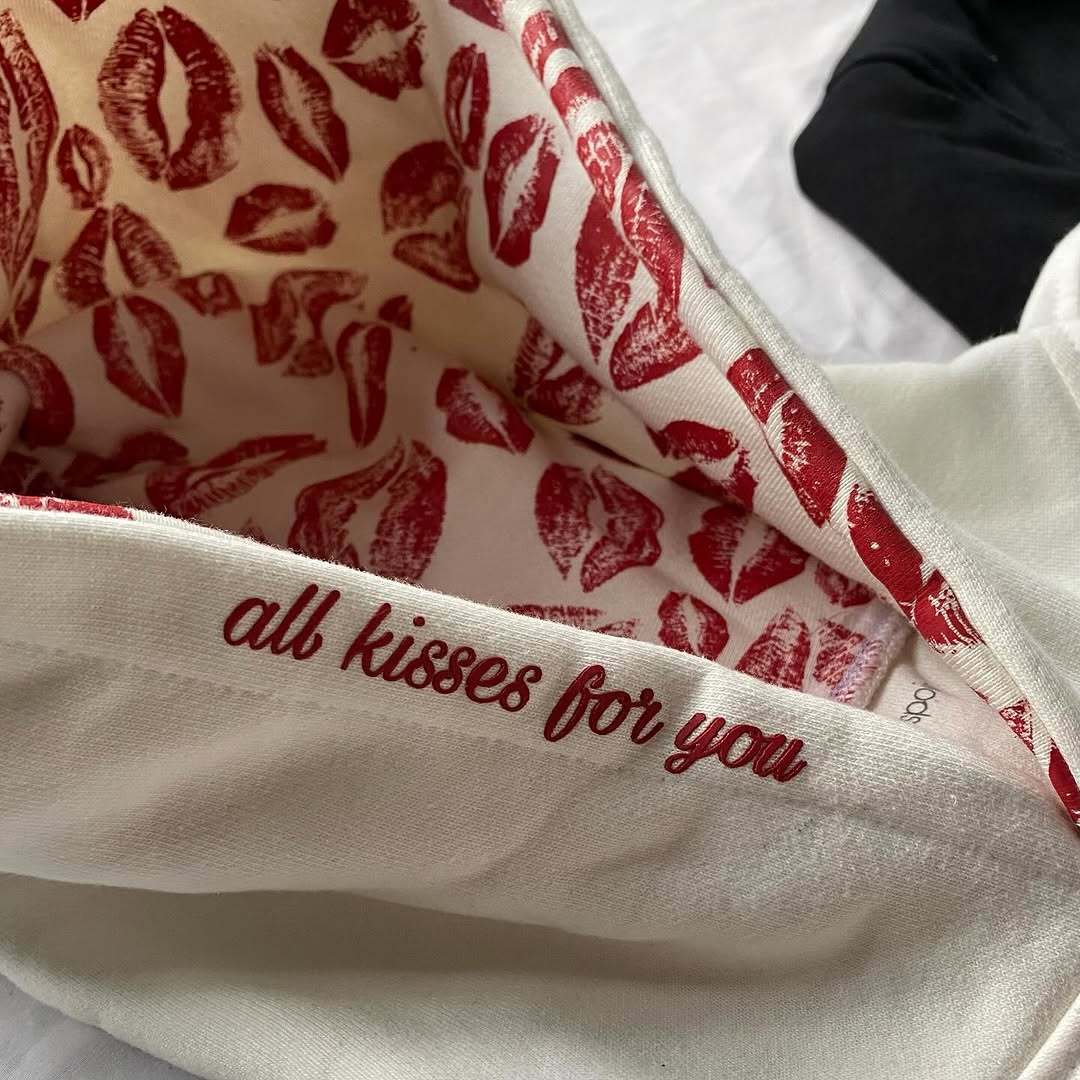 Textile with red lip prints and 'all kisses for you' text on a white background