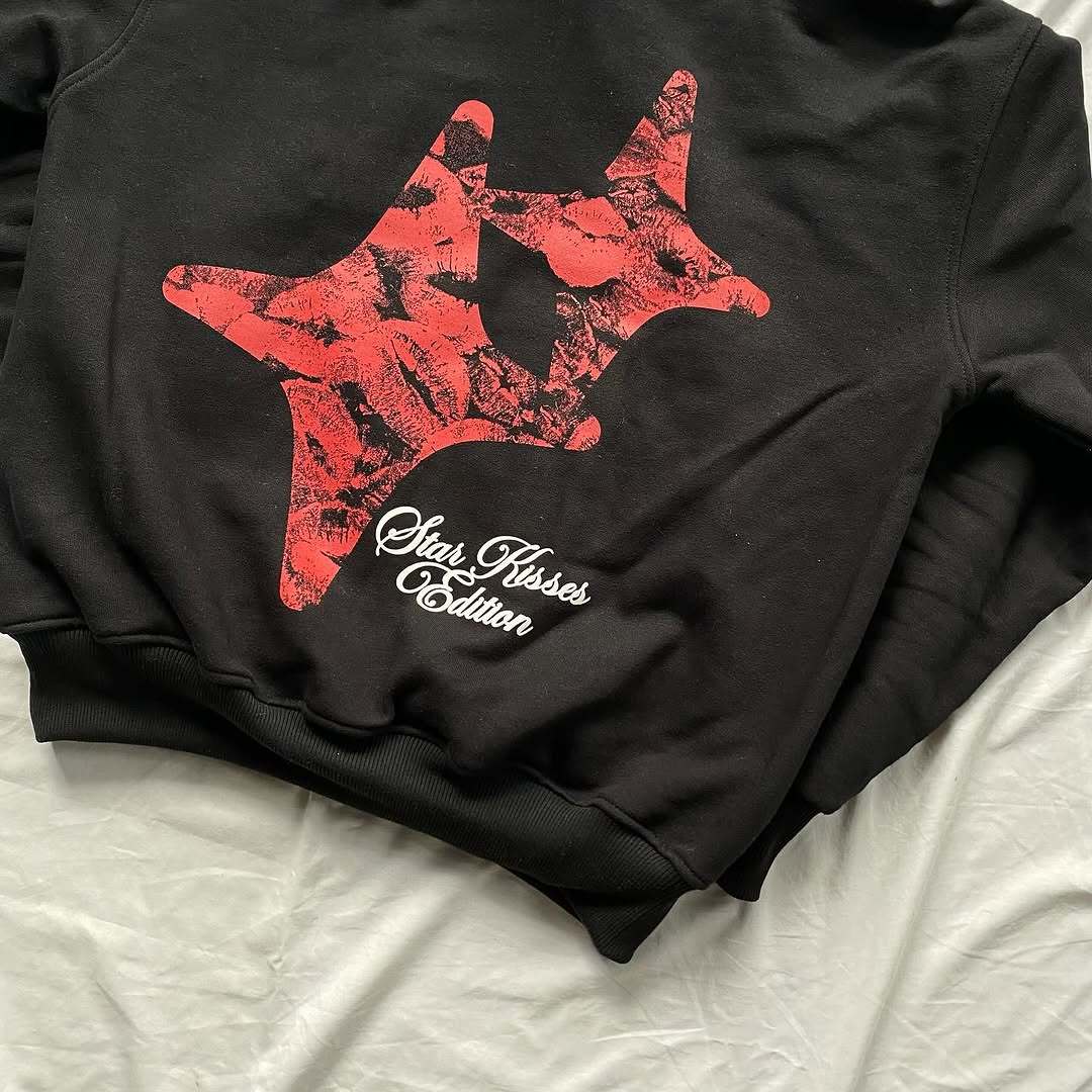 Black sweatshirt with red star design and text on a white surface