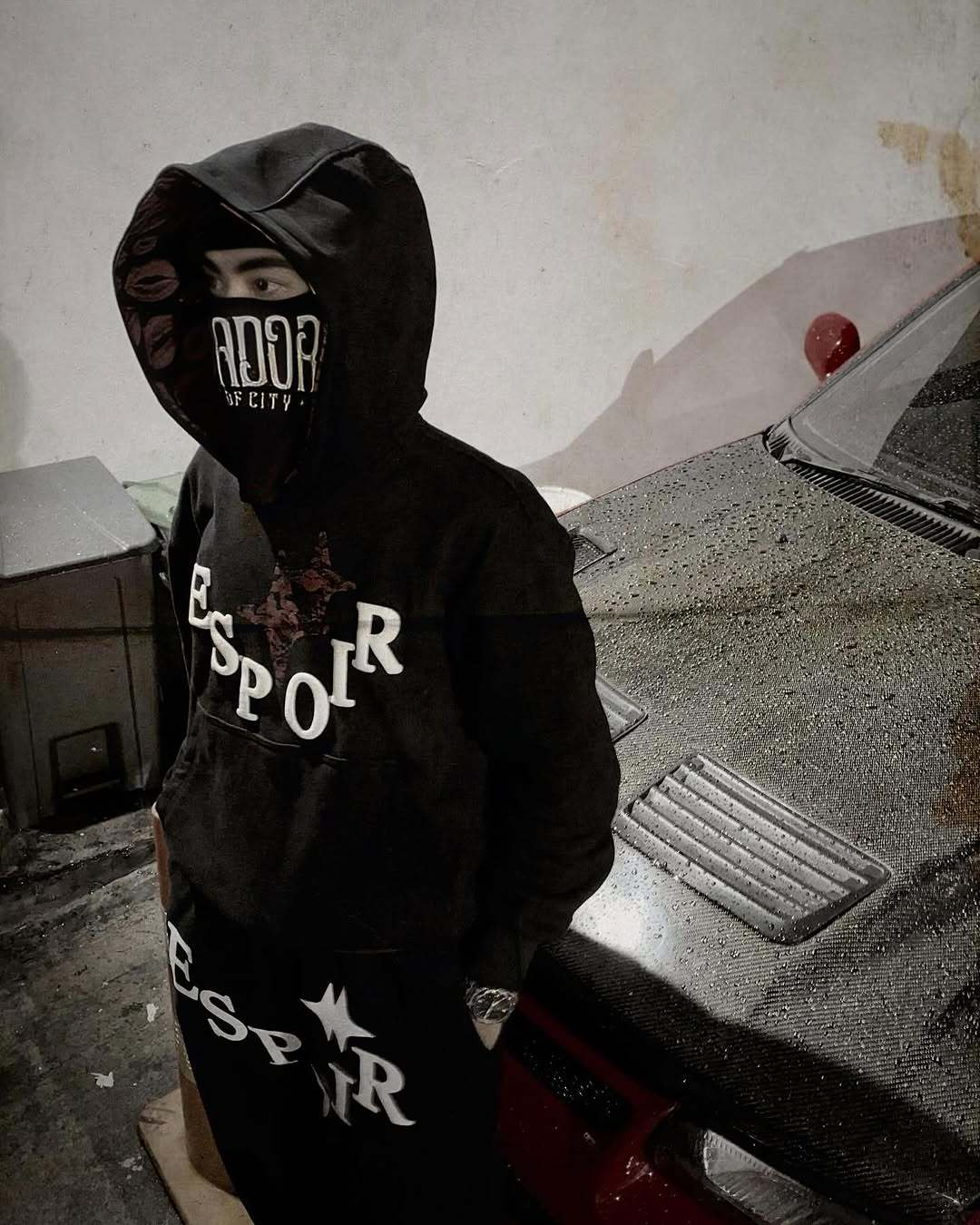 Person wearing a black hoodie with 'ESPOIR' branding in an urban setting.