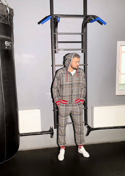 Person in plaid tracksuit using pull-up bar in home gym setting