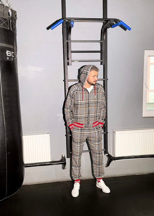 Person in plaid tracksuit using pull-up bar in home gym setting
