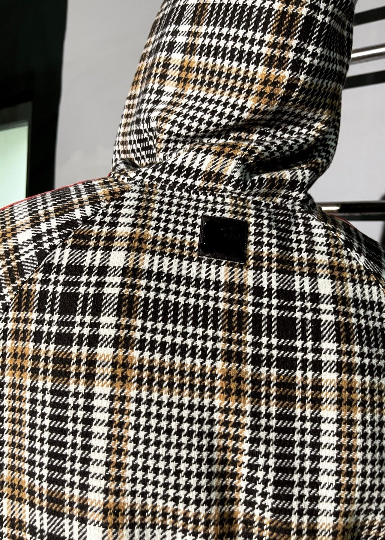 Houndstooth patterned coat with a hood on a neutral background