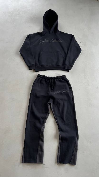 Black hoodie and pants set on a light gray surface