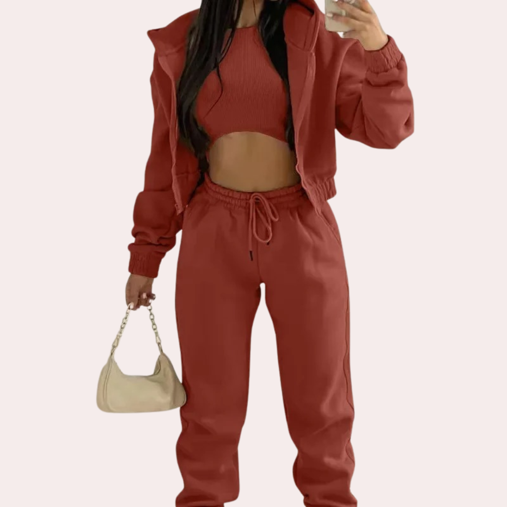 Person wearing a red tracksuit holding a beige handbag on a white background