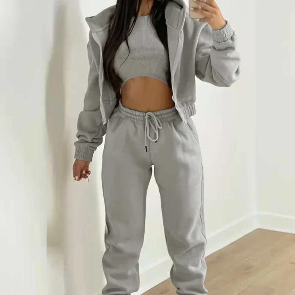 Person wearing a gray tracksuit against a white background