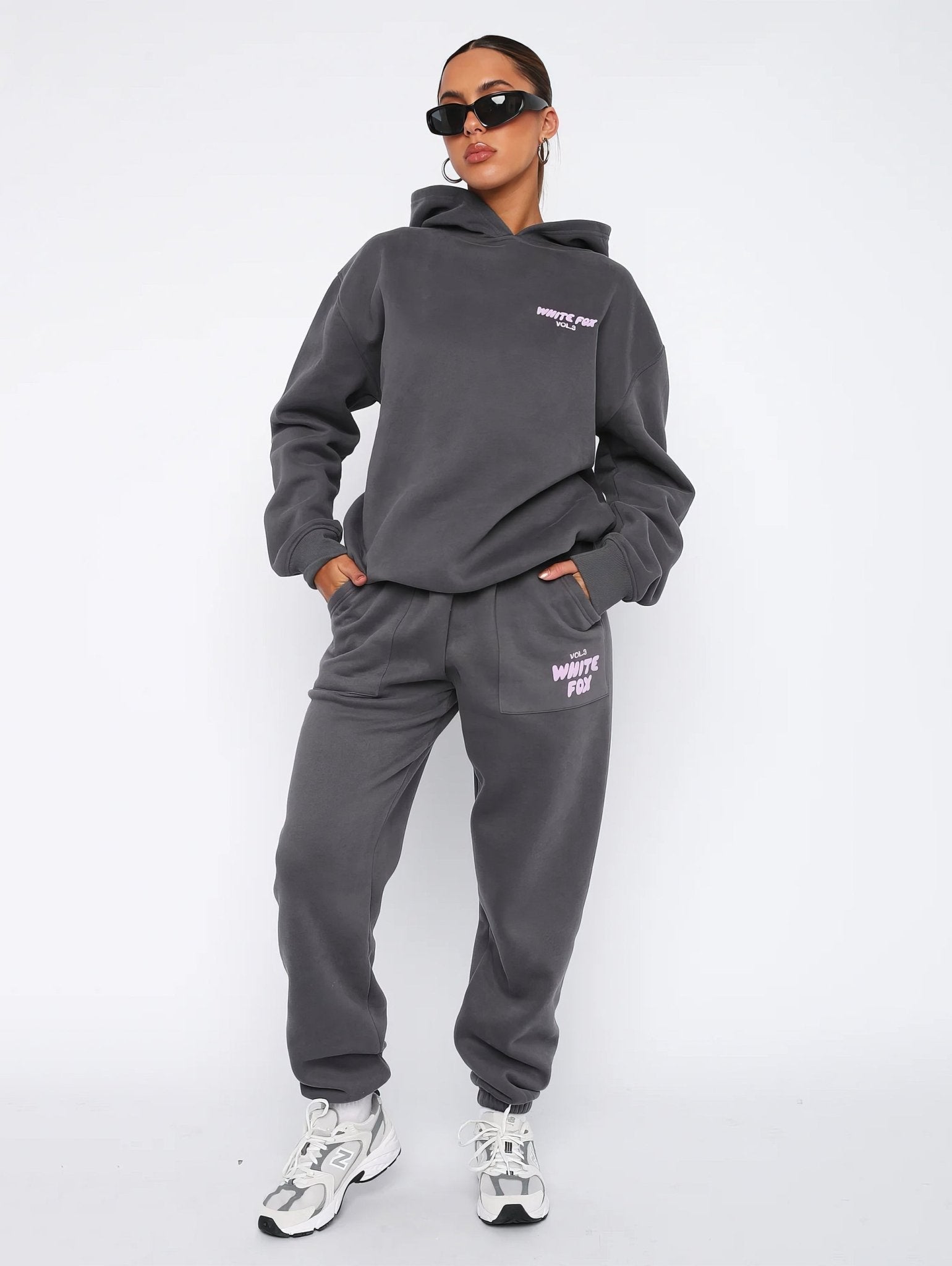 Person wearing a gray tracksuit with brand logo on a white background