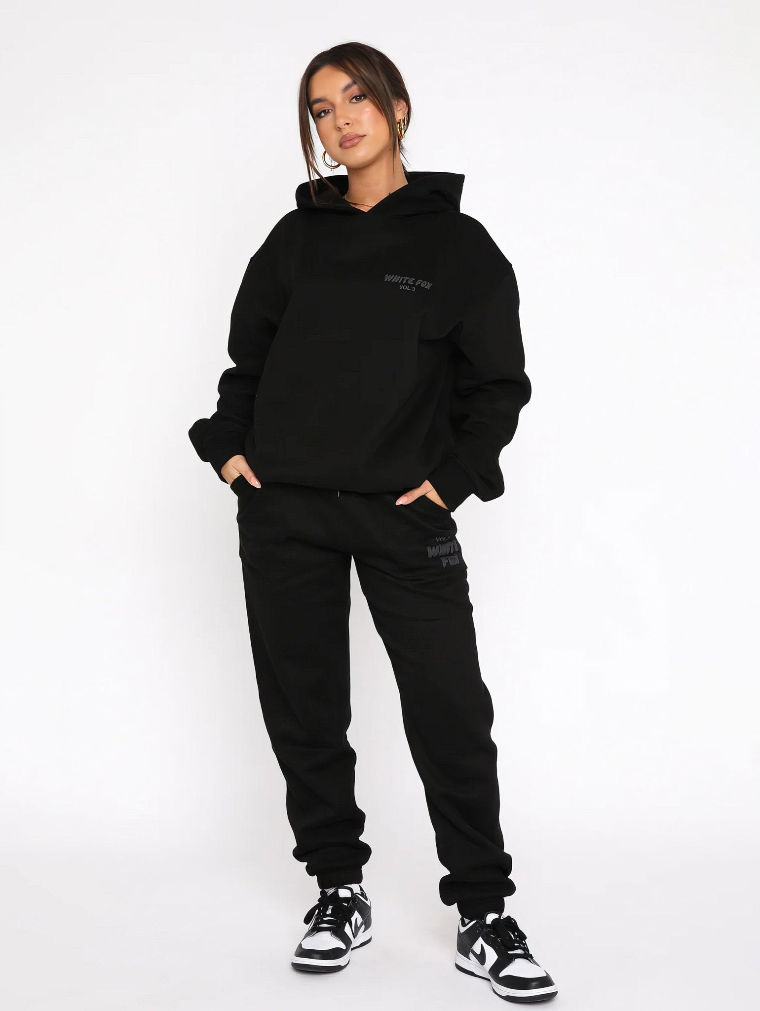 Person wearing a black hoodie and black pants on a white background