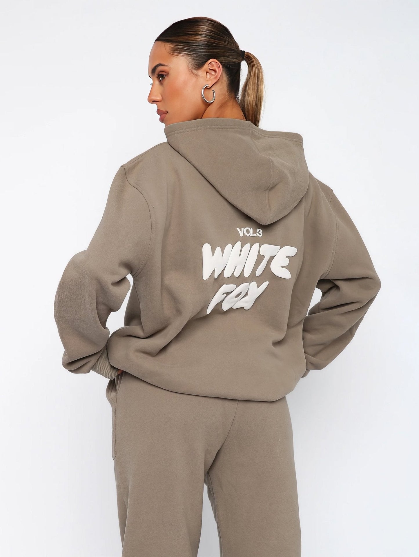 Person wearing a beige hoodie with 'White Fox' text on the back against a white background