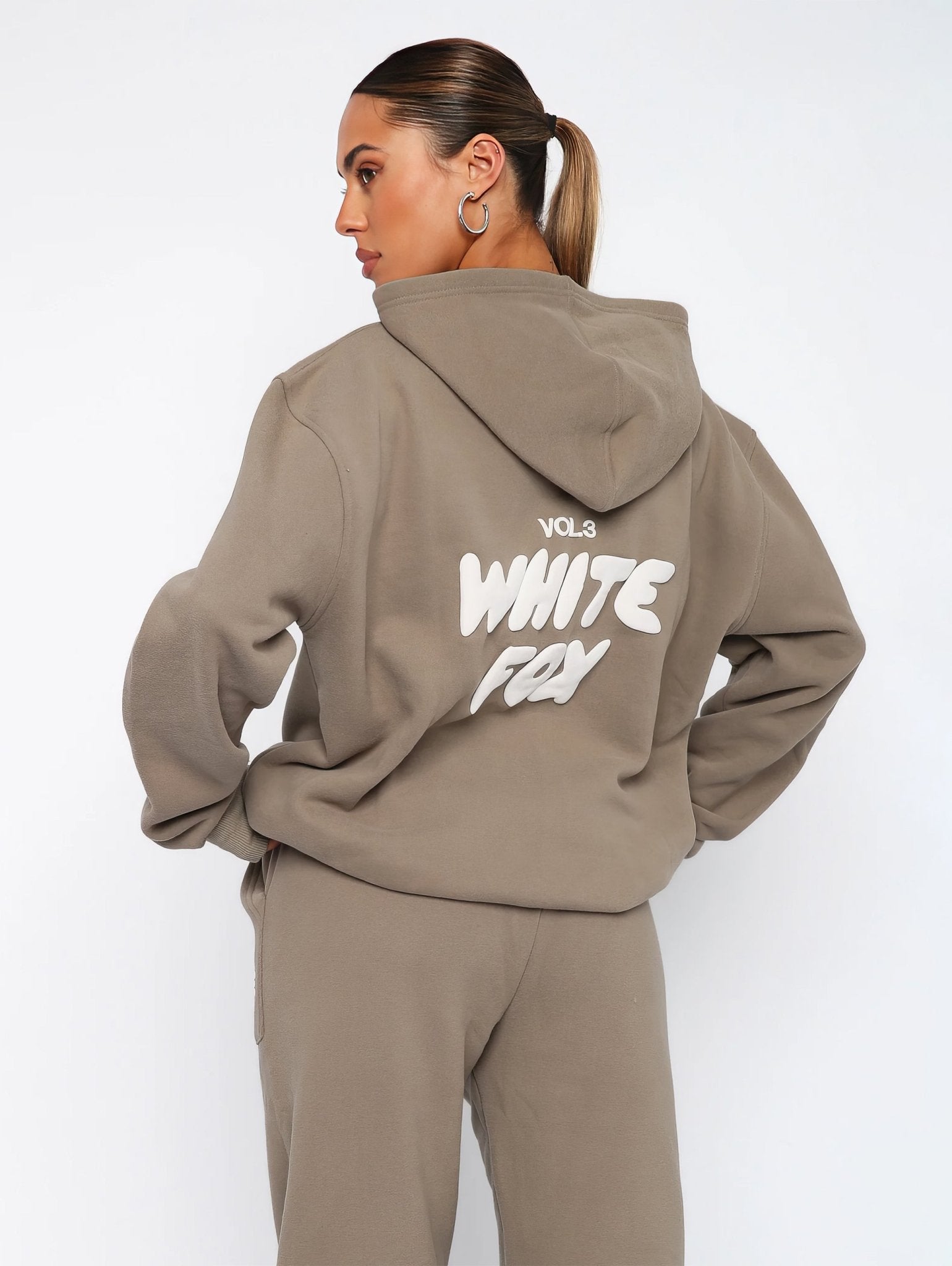 Person wearing a beige hoodie with 'White Fox' text on the back against a white background