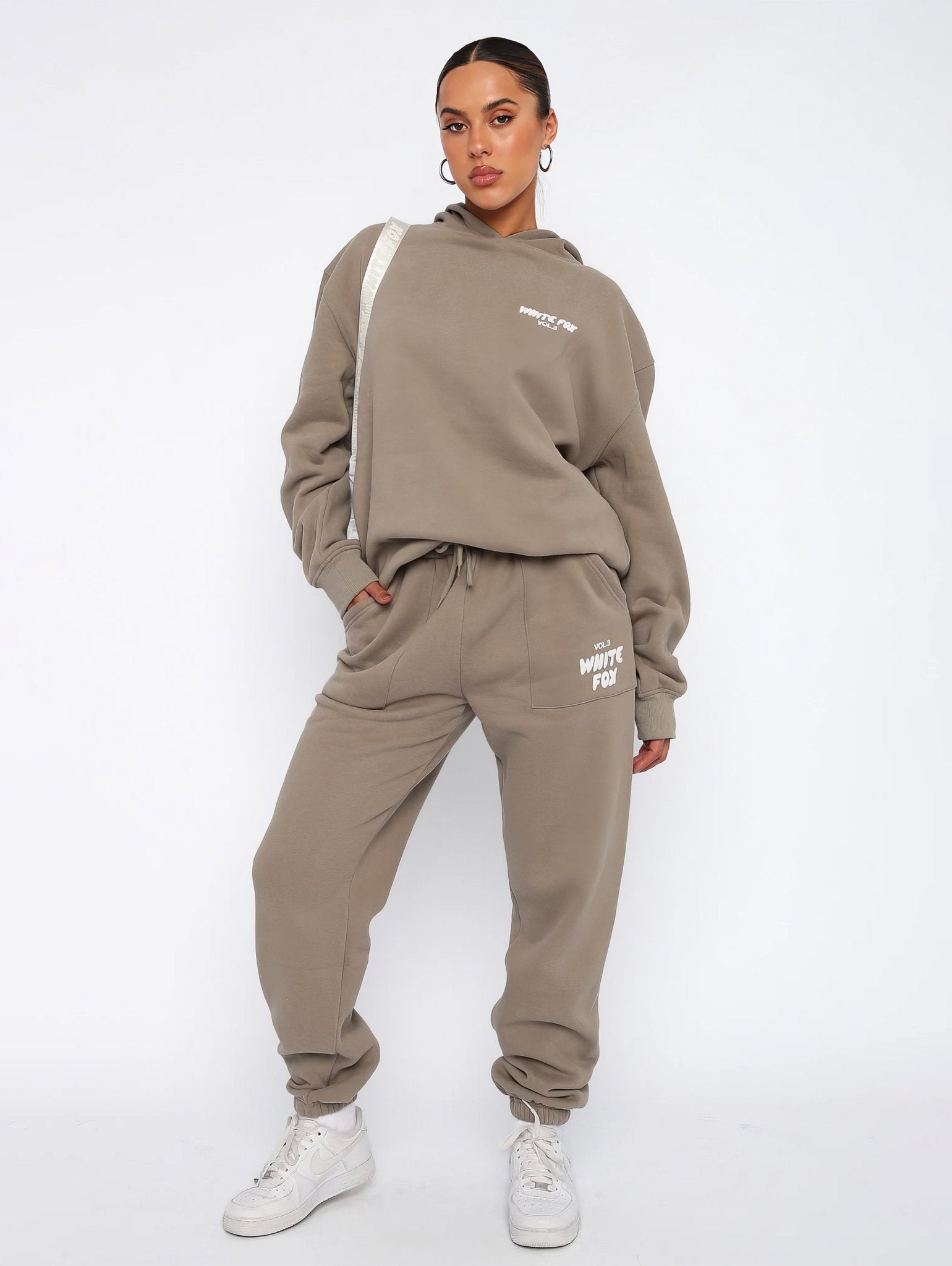 Person wearing a beige tracksuit with white text on a white background