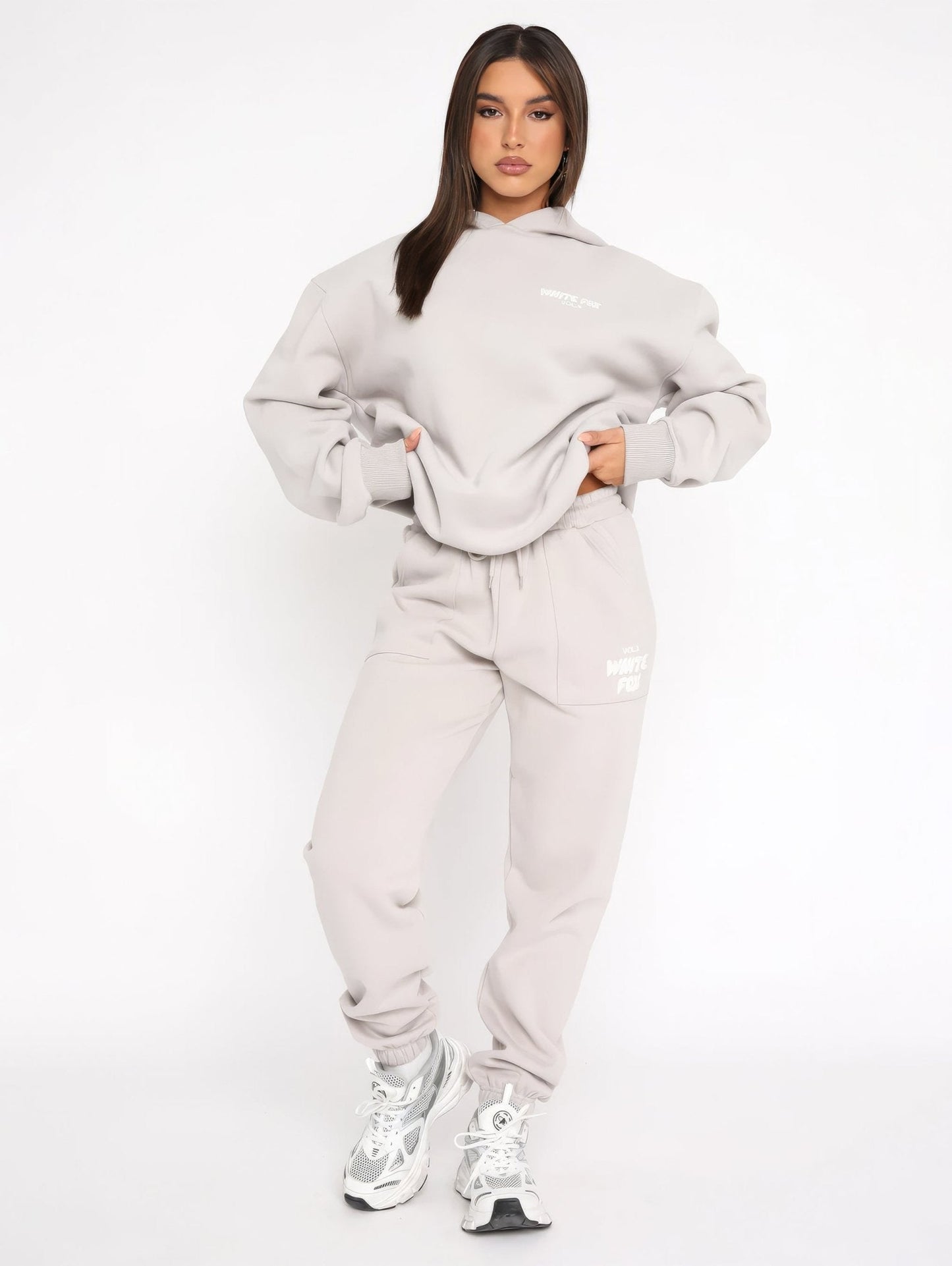 Woman wearing a gray tracksuit with white sneakers on a white background