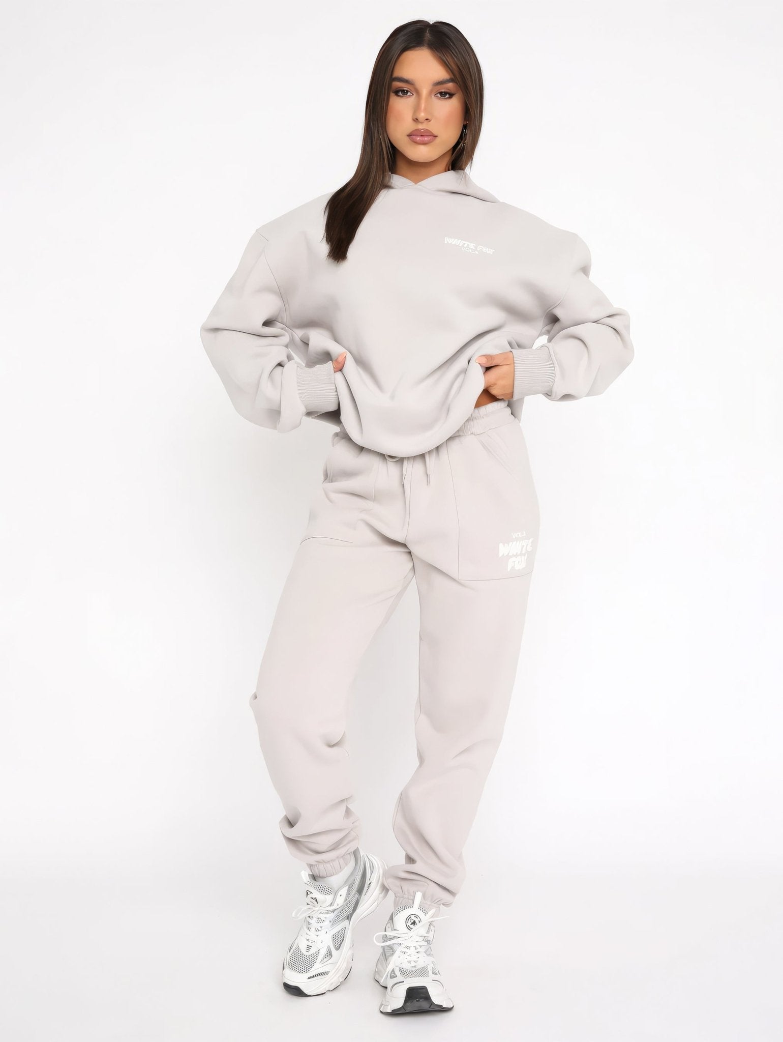 Woman wearing a gray tracksuit with white sneakers on a white background