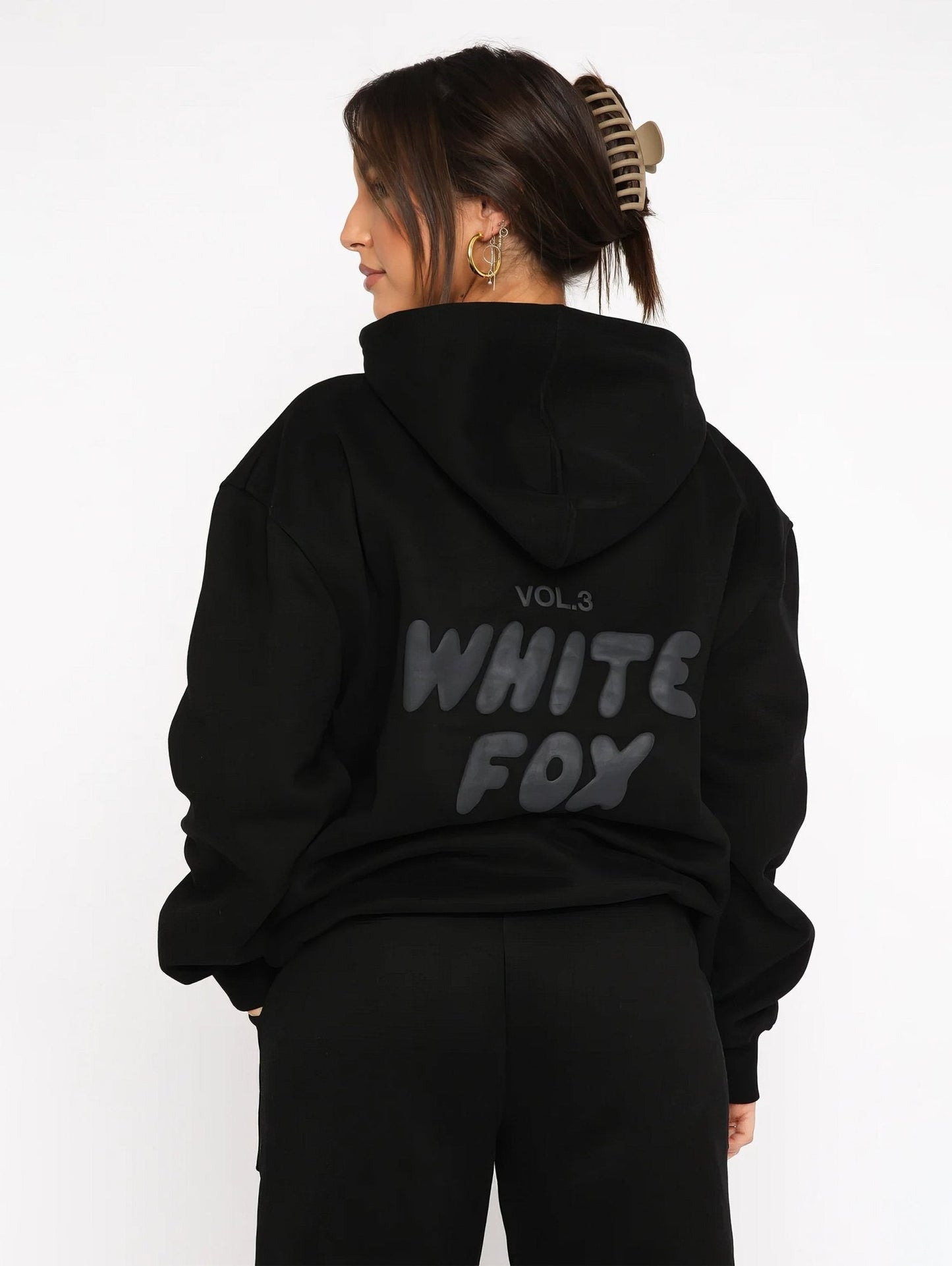 Person wearing a black hoodie with 'White Fox' text on the back against a white background