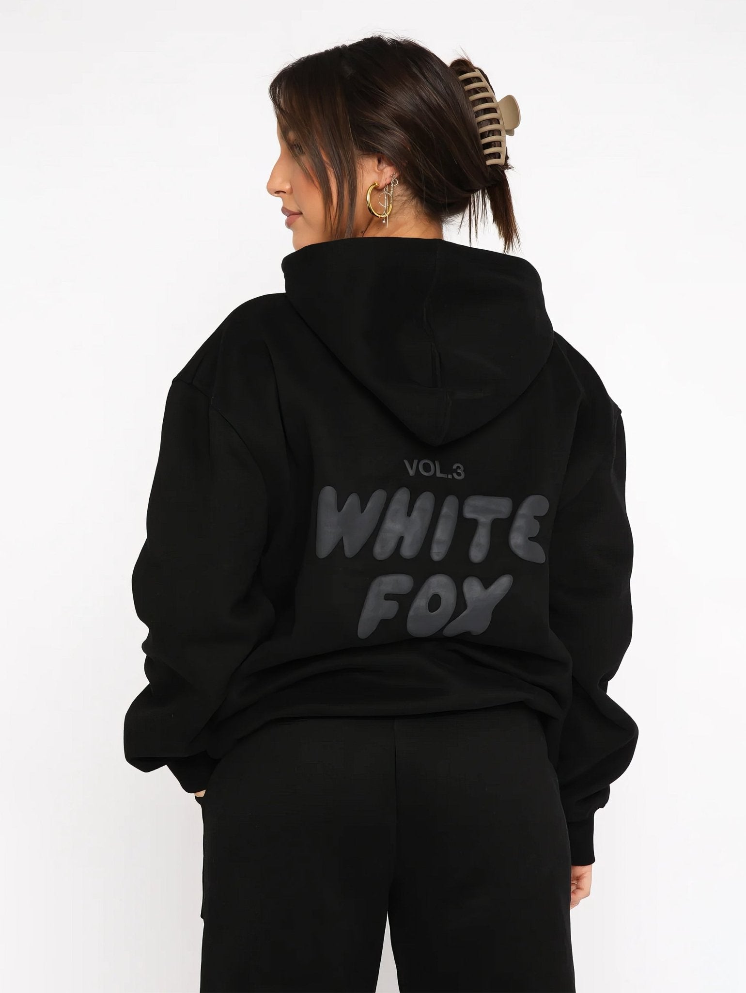 Person wearing a black hoodie with 'White Fox' text on the back against a white background