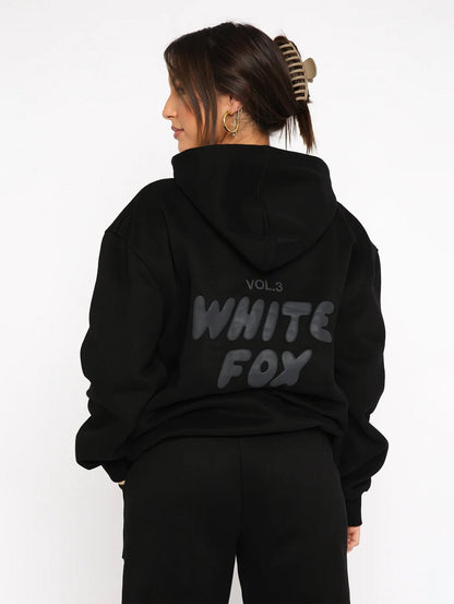 Person wearing a black hoodie with 'White Fox' text on the back against a white background