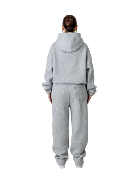 Person wearing a gray tracksuit on a white background
