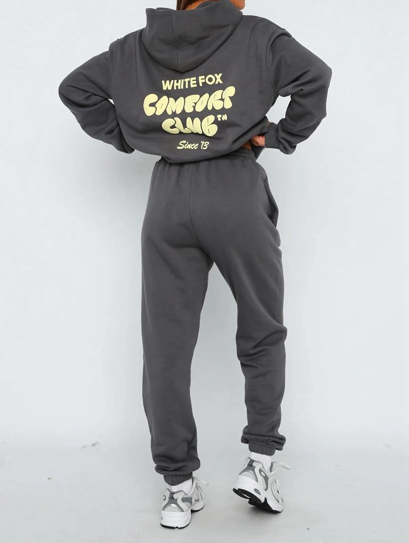 Person wearing a gray hoodie and pants with branding on a white background