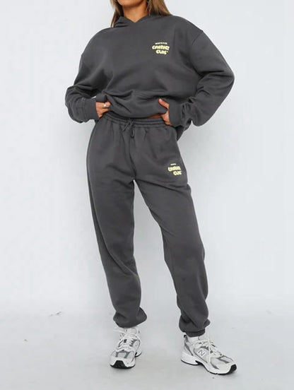 Person wearing a gray sweatshirt and pants set with brand logo on a white background