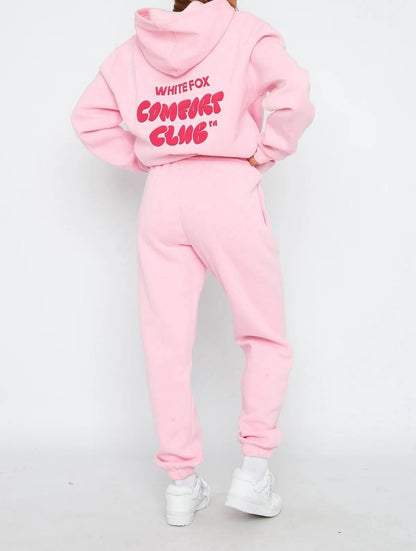 Pink hoodie and jogger set with 'White Fox Comedy Club' text on a white background