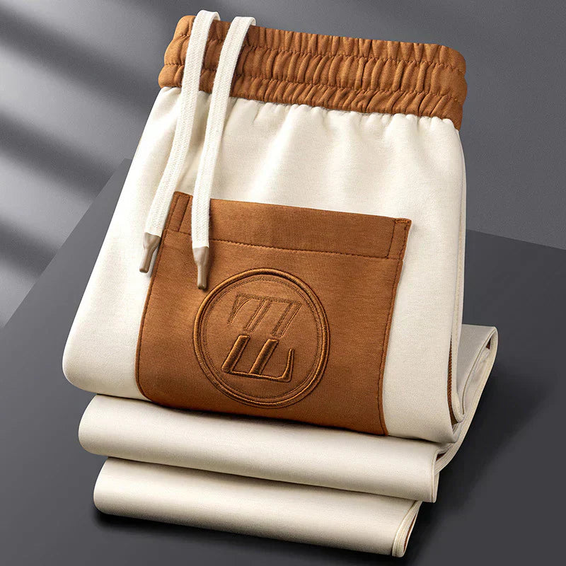 Folded beige and brown shorts with a logo on a gray background