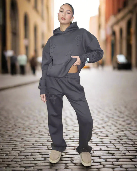 Person wearing a dark gray hoodie and pants on a cobblestone street.